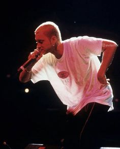 a male in a white shirt and black pants on stage with a microphone to his side