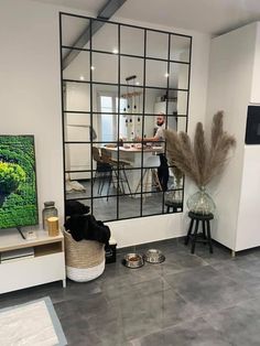 a man standing in front of a large mirror next to a dog on the floor