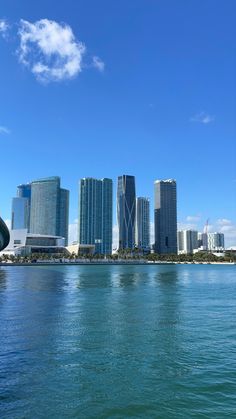 the city skyline is seen from across the water in front of tall buildings and skyscrapers