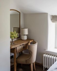 a bedroom with a desk and chair next to a window near a radiator