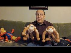 a man sitting on a couch with balloons in the shape of monkeys and monkey heads