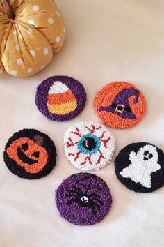 six crocheted halloween coasters are arranged on a table with a pumpkin in the background