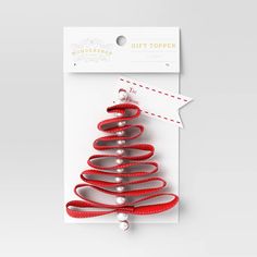 a red ribbon christmas tree ornament on a white card with a gift tag