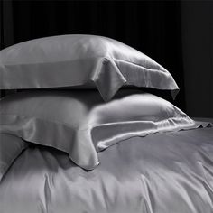 two pillows are stacked on top of each other in front of a black background with white sheets