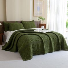 a bed with green bedspread and pillows in a room