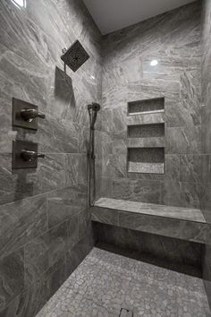 a walk in shower sitting next to a tiled floor and wall with shelves on each side