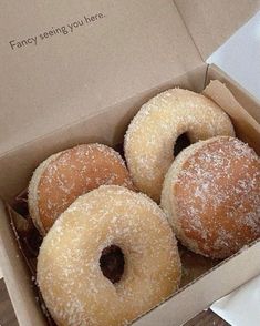 four donuts in a box with powdered sugar on them