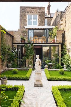 an outdoor courtyard with lots of greenery and a statue in the middle of it