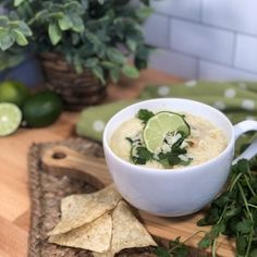 a white bowl filled with soup next to tortilla chips and cilantro