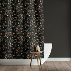 a black shower curtain with oranges and flowers on it in front of a white toilet