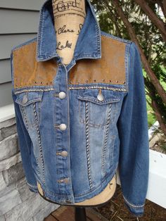 denim jacket with beaded frindge on back and vegan leather on back and front yokes with black rhinestones on front yokes. This is a womans sizeXL Fitted Distressed Denim Jacket For Fall, Embellished Medium Wash Denim Jacket For Fall, Fitted Denim Jacket For Rodeo, Fall Rodeo Denim Jacket In Medium Wash, Fall Rodeo Medium Wash Denim Jacket, Medium Wash Denim Jacket For Rodeo In Fall, Embellished Denim Jacket For Fall, Western Style Denim Jacket For Rodeo In Fall, Western Style Denim Jacket For Rodeo