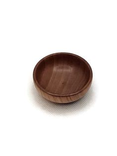 a small wooden bowl sitting on top of a white table