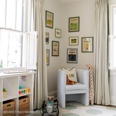 a child's room with pictures on the wall and a chair in front of it