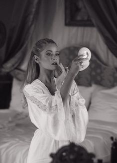 a woman brushing her teeth in front of a mirror while holding an object up to her mouth