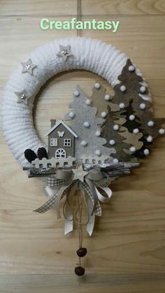 a christmas wreath hanging from the side of a wooden wall with a house on it