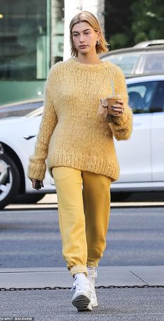 a woman walking down the street while holding a drink