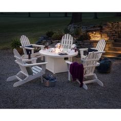 an outdoor table and chairs set up outside at night with fire pit in the background