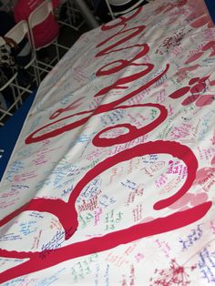 a large sign with writing on it and people sitting at tables in the back ground