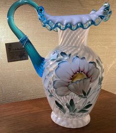 a blue and white glass vase sitting on top of a wooden table next to a sign