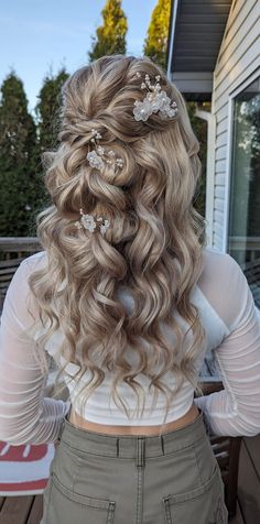 the back of a woman's head with long hair and flowers in her hair