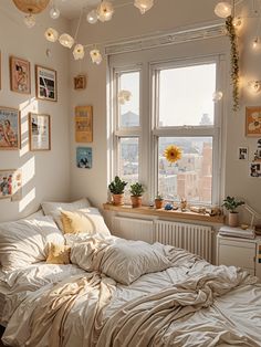 an unmade bed in a small room with pictures on the wall and lights hanging from the ceiling