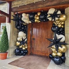 an entrance decorated with black, gold and white balloons