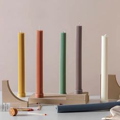 the candles are lined up next to each other in different colors and sizes, along with matchesticks