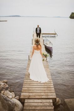 the bride and groom are walking down the dock