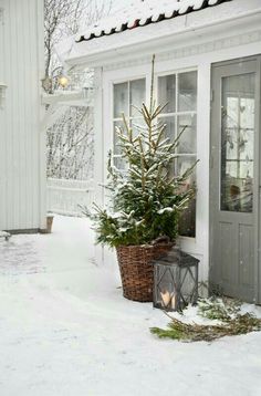 a small christmas tree is in a basket next to a door with a lit candle