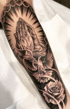 a person with a tattoo on their arm that has a praying hand and roses in it