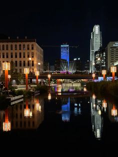 the city is lit up at night with lights reflecting in the water and buildings on both sides