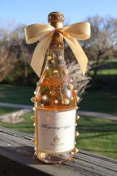 a bottle of wine with a bow on it sitting on a wooden table in front of some grass