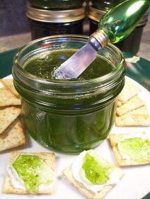 a jar filled with green liquid sitting on top of a white plate next to crackers