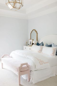 a white bed sitting in a bedroom under a chandelier