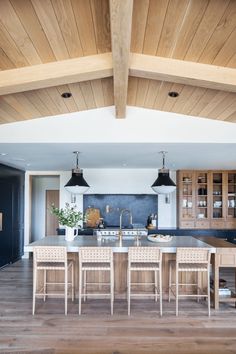 a large kitchen with an island in the middle and wooden ceiling beams on both sides