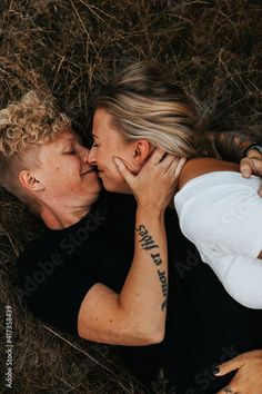 a man and woman laying on the ground with their heads close to each other kissing