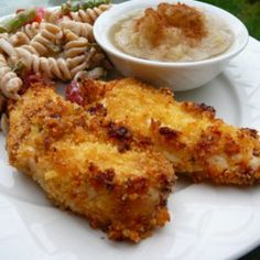 a white plate topped with fried chicken and pasta next to a bowl of macaroni and cheese