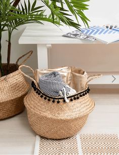 two woven baskets sitting on top of a white floor next to a potted plant