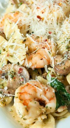 pasta with shrimp, mushrooms and parmesan cheese in a white bowl on a table