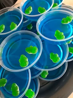 several plastic plates with green frog lids on them sitting on a metal tray filled with blue water