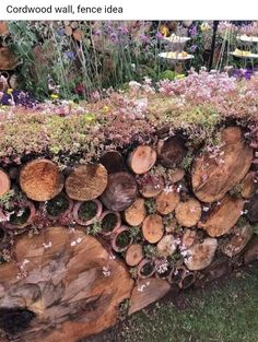 a large pile of wood sitting on top of a lush green field next to flowers