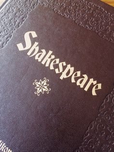 an old shakespeare book sitting on top of a wooden table