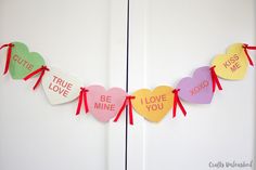 valentine's day decorations hanging on the front door with red ribbon and paper hearts that say, true love be mine