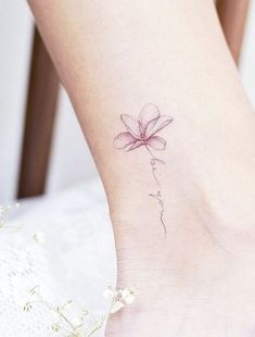 a woman's foot with a flower tattoo on the side of her leg,