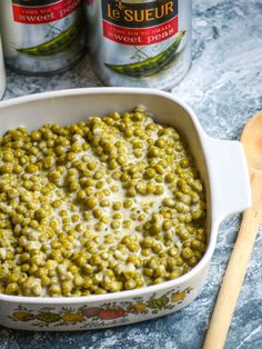 a casserole dish filled with green beans and cream next to two cans of soup