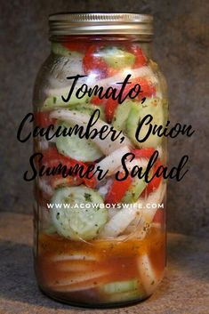 a mason jar filled with sliced cucumber, onion and tomato salad in it