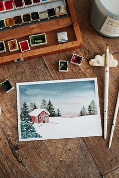 watercolors and paint supplies on a wooden table next to a cup of coffee