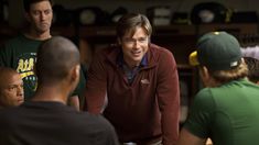 a group of young men standing around each other in a room with one man smiling at the camera