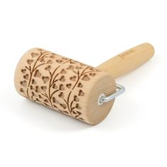 a wooden rolling pin with leaves and vines engraved on the side, sitting on a white surface