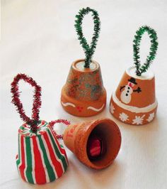 three small christmas decorations are sitting on a white tablecloth and one is made out of clay